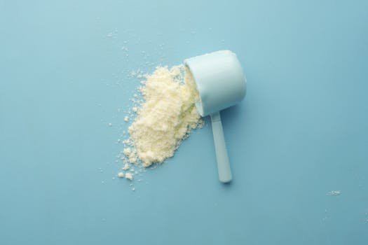 Scoop of protein powder being poured into a shaker bottle next to gym equipment, symbolizing effective use of protein powder for muscle gain.