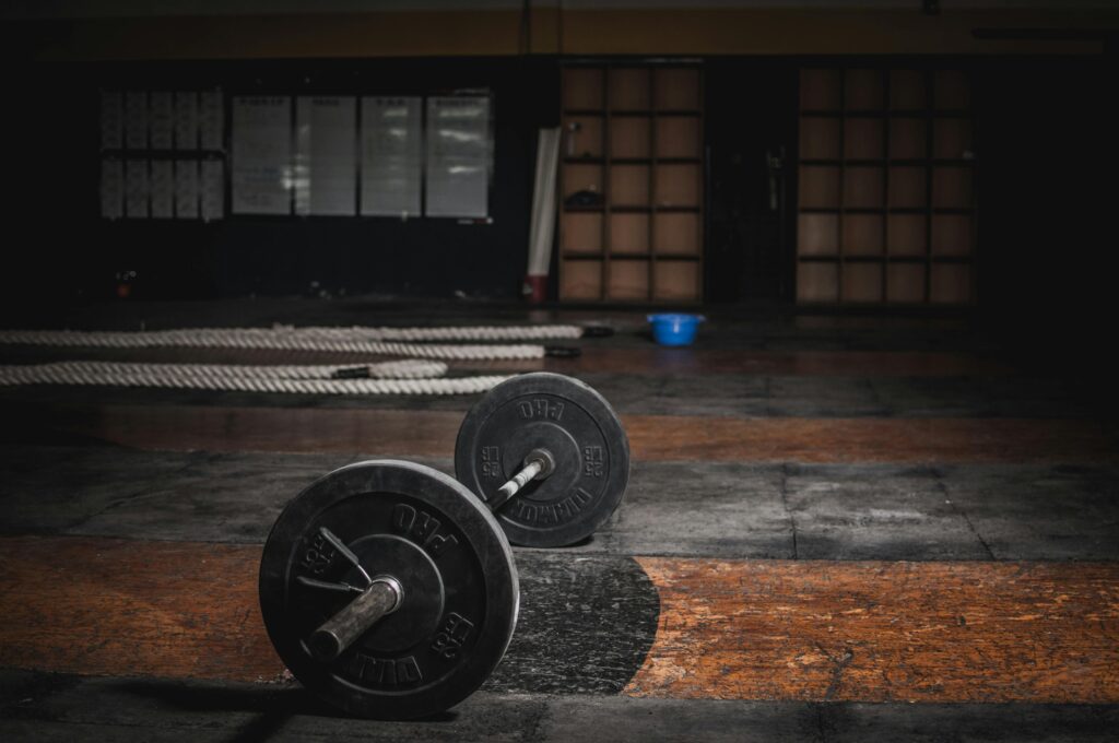 Home gym essentials layout including dumbbells, resistance bands, yoga mat, kettlebell, and bench in a clean modern workout space.